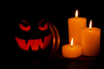 Carved Halloween pumpkin lights inside with flame on a black background. Celebration of Halloween. Pumpkin head jack lantern with burning candles in the dark room