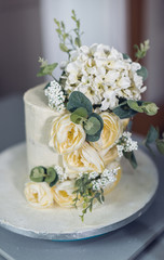Fototapeta na wymiar A beautiful and exquisite mouth watering hand made wedding celebration cake packed full, with yellow roses, green and cream flowers, on an iced silver base. Organic wedding cake art