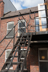 urban new york  style metal vintage steel fire escape ladder stairs in manchester england. Fire escape route on the side of a building saves lives.