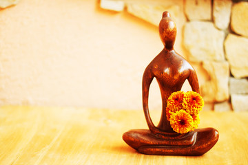 Small female Buddha wooden statuette with flowers in pastel colors - beautiful zen concept