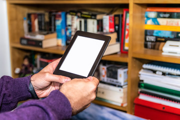 Male hands holding digital reading device in front of bookshelves