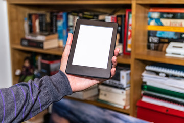 Male hands holding digital reading device in front of bookshelves