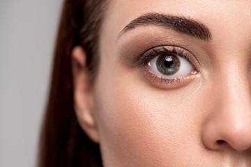 close up view of eye on female face, isolated on grey