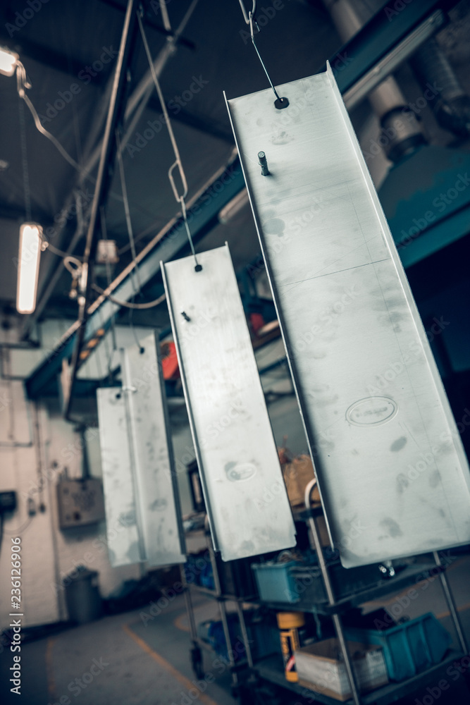 Wall mural Industrial sheet metal steel products on a production line in an industrial factory setting, with atmospheric lighting. Being prepared for paint treatment. Industrial sheet metal.