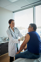Obraz premium Doctor giving male patient a shot in the arm