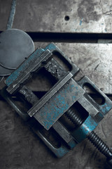 A dirty well used moody and atmospheric blue oily industrial vice in a dark photographic setting, photographed from above. Cinematic lighting. Industry.