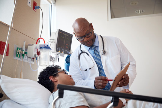 Patient talking to doctor while lying on hospital bed