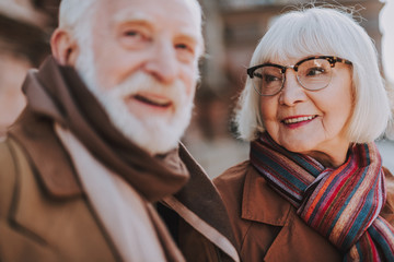 Portrait of elderly woman in glasses looking at husband and smiling. Focus on lady