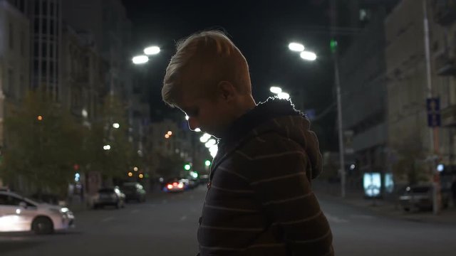 Sad missed kid standing on street, lost in big city, police patrol search slowmo