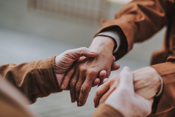 Tender moment. Close up of loving elderly couple holding hands on the street