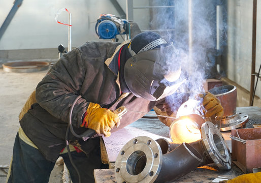  The professional welder works with manual-arc welding. Welds the pipe with the transition DN150. Butt weld.