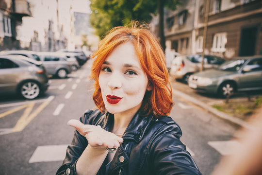 portrait of fashionable young woman wearing a leather jacket taking selfie with smartphone