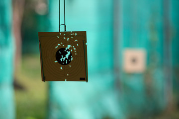 Shooting paper targets with holes in the middle from accurating shoots in a gun shooting range from a shooting practice field. Seeing a green slate a background.
