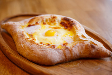 Adjarian open khachapuri with egg on wooden board