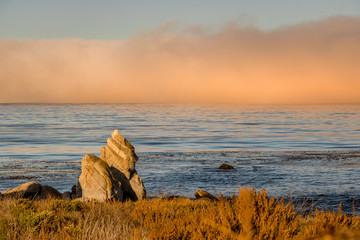 A thick fog is rolling over the ocean near Carmel River Beach in Carmel by the Sea, California