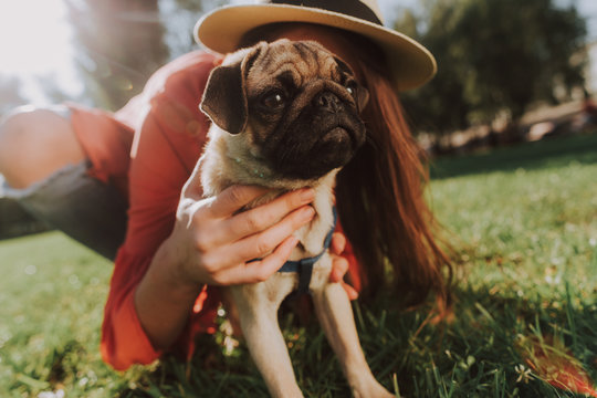 Close up of young girl hugging her pug while spending time together outdoors
