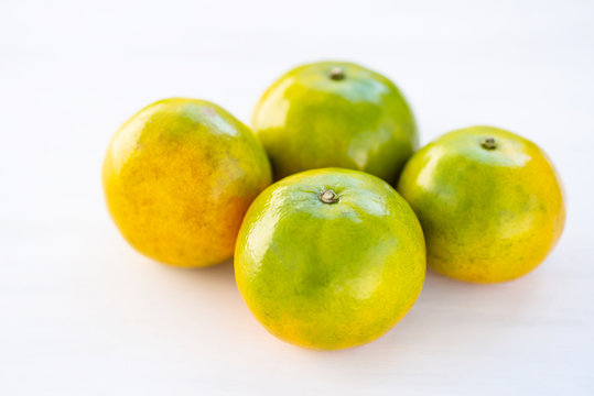 Green tangerine orange fruit on white table