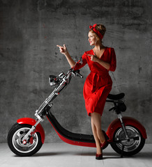 Fototapeta na wymiar Woman ride sit on motorcycle bicycle scooter pinup retro style pointing fingers laughing smiling red dress 