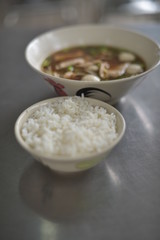 A stream jasmine rice bowl served with a bowl of pork balls in a brown soup.