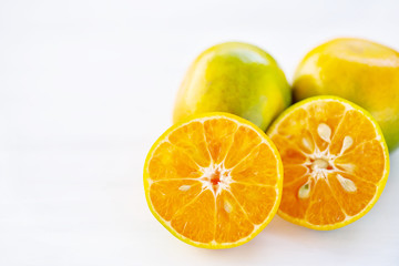Half of green tangerine orange fruit on white table