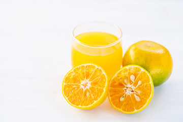 Sliced tangerine orange fruit and juice on white table