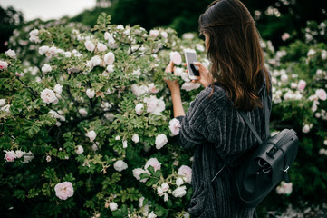 Young girl taking pictures of flowers on phone
