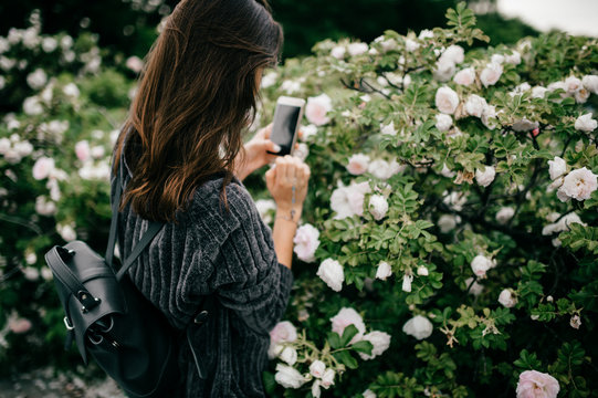 Young girl taking pictures of flowers on phone