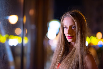 Portrait of a beautiful mature woman at night with the city lights in the background.