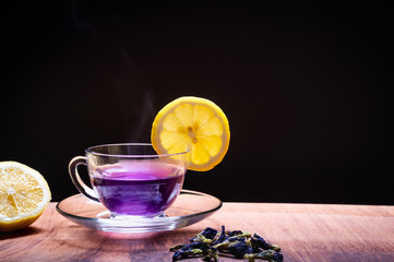 Cup of Butterfly pea flower tea with lemons on wooden background. Health drink concept.