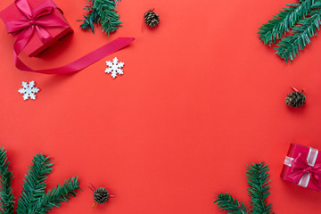 Table top view of Merry Christmas decorations & Happy new year ornaments concept.Flat lay essential difference object fir tree and gift box & snow ice on modern red paper background.copy space design.