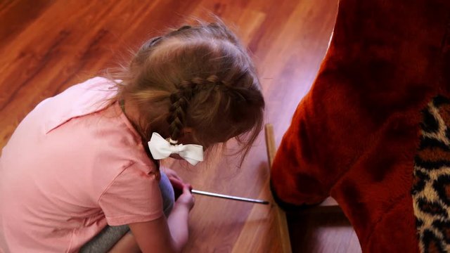 A little girl repairs a toy deer. A baby turns screw with a screwdriver.