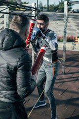 Fototapeta na wymiar Full length of the active sportsman training with red boxing sticks