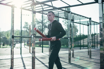 Calm man in sports clothes holding two boxing sticks