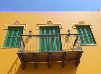 Obraz na płótnie Canvas Yellow Building with Balcony and Green Window Shutters 