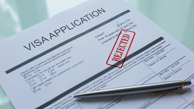Visa application document rejected, hand stamping seal on official paper closeup
