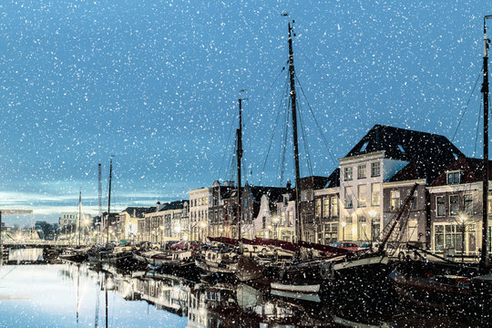 Snowfall image of a Dutch canal with sailing boats in the city of Zwolle