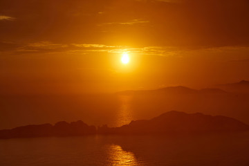 Fototapeta na wymiar Sunset over the sea. Bright colorful background with sun, sea and rocks