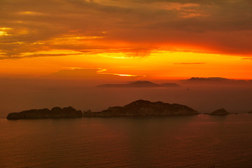 Naklejka na ściany i meble Sunset over the sea. Bright colorful background with sun, sea and rocks