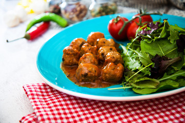 Meatball, bacon and potatoes with lettuce on white plat