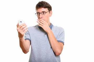 Studio shot of man holding mobile phone looking shocked