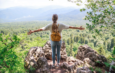 Girl Hiking in the mountains. Girl with a yellow backpack on the background of the mountain landscape.