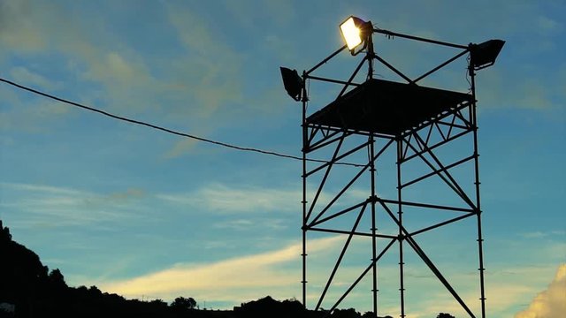 Close uo footage of a spotlight with a dusk sky behind it.