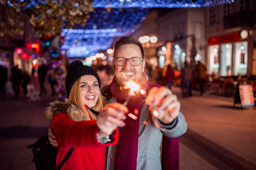 Lovely young couple with sparklers on city street.