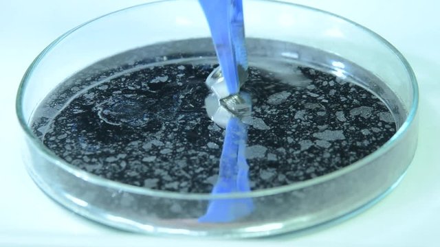A metal nut and a glass marble floats on the surface of mercury in a shale; the buyance of mercury lets even steel float.