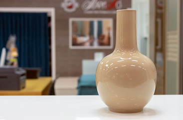 Beige ceramic vase of simple form on a white table.