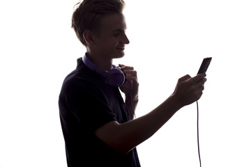 silhouette of a young man with headphones on his neck,a guy flips through a playlist of music on his player on white isolated background