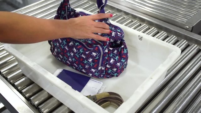 Woman Takes Out Her Things From White Tray At  Airport Security Check. Female Hands Taking Bag, Passport, Boarding Pass, Belt. Real Time 4k Video Footage.