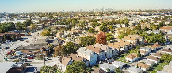 Naklejka premium Panorama widok z lotu ptaka tradycyjnej dzielnicy mieszkalnej na zachód od Chicago. Rząd klasycznego domu z ogrodem i garażem wolnostojącym. Linie horyzontu od śródmieścia w tle