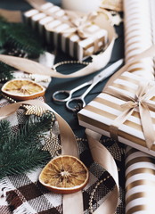 Decor for christmas gifts. Golden paper  gift boxes and decor on the wooden table. Christmas background with decor.