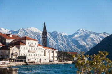 Naklejka na ściany i meble Winter in Montenegro. Perast in the Bay of Kotor with snow peaks of mountains, blue cold the Adriatic Sea, old town with ancient architecture, stone houses and tiled roofs.